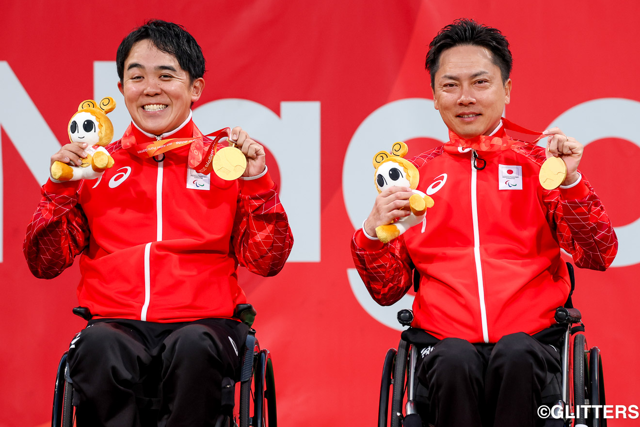 互いを「かけがえのないパートナー」「憧れの先輩」と呼び合う川野将太(左)と宇佐美慧(右)が、表彰台で金メダルを掲げる | 車いすテニス クアードの川野将太と宇佐美慧がダブルスで涙の金メダルに輝く|愛知・名古屋2026アジアパラ競技大会 | Glitters 障害者スポーツ専門ニュースメディア